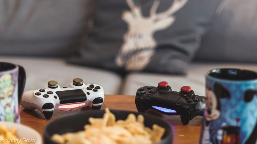 A couple dualshock 4 controllers next to some coffee and snacks
